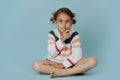 Secretive little girl sitting cross-legged with index finger over her lips
