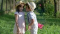 Secrets of children, little boy whispers in ear to the girl and holding the flower behind her back in summer park