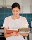 These are the secrets to achieving deliciousness. Shot of a young woman reading a cook book. Royalty Free Stock Photo