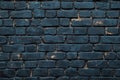 A section of a blue brick wall with a single yellow light on top Royalty Free Stock Photo