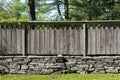 Section of Stacked Stone Wall with Distressed Wood Fence. Royalty Free Stock Photo