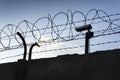 Security camera behind barbed wire fence around prison walls Royalty Free Stock Photo