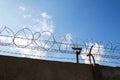 Security camera behind barbed wire fence on the wall, prison, security, crime or illegal immigration concept, blue sky Royalty Free Stock Photo