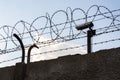 Security camera behind barbed wire fence on the wall, prison, security, crime or illegal immigration concept, blue sky Royalty Free Stock Photo