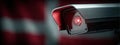 Security camera captures red light in front of flag in a public area during daylight Royalty Free Stock Photo