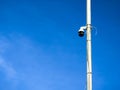 Security camera mounted on a pole against a clear blue sky backdrop Royalty Free Stock Photo