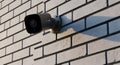 Security camera mounted on a white brick wall. The camera is Royalty Free Stock Photo