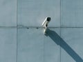 Security cctv camera on blue concrete wall casting long shadow Royalty Free Stock Photo