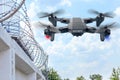 Security drone patrols the territory across the sky. Guarding the wall with barbed wire drone with blue and red beacon Royalty Free Stock Photo