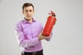 Young man holding a fire extinguisher in his hands isolated on a light background Royalty Free Stock Photo