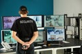 Security guard with portable radio transmitter monitoring modern CCTV cameras in surveillance room Royalty Free Stock Photo