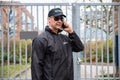 Security Guard Talking On Mobile Phone In Front Of Gate Royalty Free Stock Photo