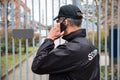 Security Guard Talking On Mobile Phone In Front Of Gate Royalty Free Stock Photo