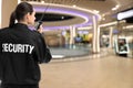 Security guard using portable radio transmitter in shopping mall