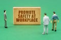 On the green surface are figures of people and a sign with the inscription - Promote Safety at Workplace Royalty Free Stock Photo