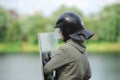 Security service specialist in uniform and helmet standing against lake