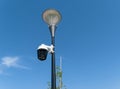 Security video camera mounted on a lamppost outdoors against a blue sky Royalty Free Stock Photo