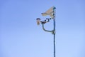 Security video camera and wind indicator against sky Royalty Free Stock Photo