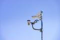 Security video camera and wind indicator against sky Royalty Free Stock Photo