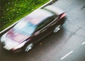 Sedan car blurry moving on wet autumnal street