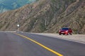 Sedan car Hyundai Solaris in red color stand on parking near asphalt road highway in Altai mountains. Travelling by car