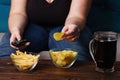 Obese woman with tv remote, junk food and beer Royalty Free Stock Photo