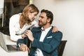 Seducing colleagues in office. Sexy blonde woman flirting with handsome smiling business man pulling him by a tie and Royalty Free Stock Photo