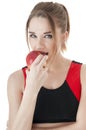 Seductive athletic girl in tracksuit eating a red apple.