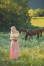 Seductive blond blue eyes lady woman in pinky airy dress on meadow of daisy chamomile holding bouquet of nflowers in hands and pos