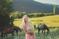 Seductive blond blue eyes lady woman in pinky airy dress on meadow of daisy chamomile holding bouquet of nflowers in hands and pos