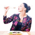 Seductive brunette beautiful woman eating sushi with chopsticks & great pleasure isolated on white background portrait Royalty Free Stock Photo