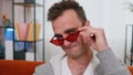 Seductive cheerful stylish man wearing red sunglasses, charming smile, blinking winking eye flirting Royalty Free Stock Photo