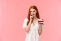 Seductive, coquettish redhead alluring girlfriend suggest try her peace cake, holding delicious dessert, biting finger Royalty Free Stock Photo