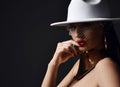 Seductive gorgeous naked woman vamp in wide-brimmed white hat with veiling and massive gold collar and earrings