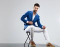 Seductive man in blue suit sitting on wooden chair Royalty Free Stock Photo