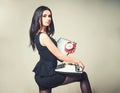 Seductive secretary holding clipboard and typewriter in her hands. Side view beautiful brunette standing with her leg