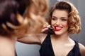 Seductive sexy young woman applying red lipstick on the lips, looking in a mirror. Retro concept. Use cosmetics Royalty Free Stock Photo