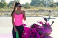 Seductive young woman in pink t-shirt poses near sport motorcycle at self service car wash in the morning. Royalty Free Stock Photo