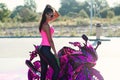 Seductive young woman in pink t-shirt poses near sport motorcycle at self service car wash in the morning. Royalty Free Stock Photo