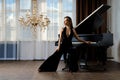 Seductive woman in sexy black jumpsuit sitting near grand piano Royalty Free Stock Photo