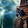 Shes a force of nature - Superhero. Seductive young woman in a black catsuit crouched on a rooftop in a lightening storm Royalty Free Stock Photo