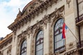 See above the Serbian flag and exterior of a building in Belgrade, Serbia, with statue in honor of Nikola Spacich.