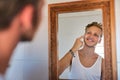 See and feel the difference after just one week. a young man applying moisturizer to his face.