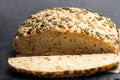 Seed covered carrot bread bloomer loaf on black stone background