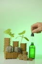 Seedling root system activator in a green glass bottle, a cucumber plant and a pipette in a hand. Fertilizer for