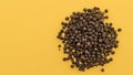 Seeds of black pepper pile on top on a yellow background, close-up, copy space Royalty Free Stock Photo