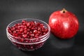 A bowel of pomegranate seeds beside a whole pomegranate fruit. Royalty Free Stock Photo