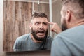 Young man feeling overemotional seeing acne on his face