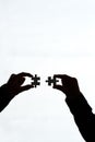 Seeing the bigger picture. Cropped shot of two people holding puzzle pieces together against a white background.