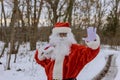 Seeing Santa Claus walking near a forest, holding a red bag filled with gifts for the children for Christmas and Royalty Free Stock Photo